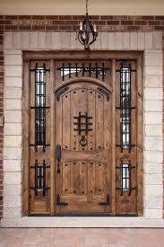 Wooden arched front door with iron accents, flanked by narrow windows in a brick entryway.