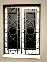 White window with black wrought-iron security bars and decorative swirls