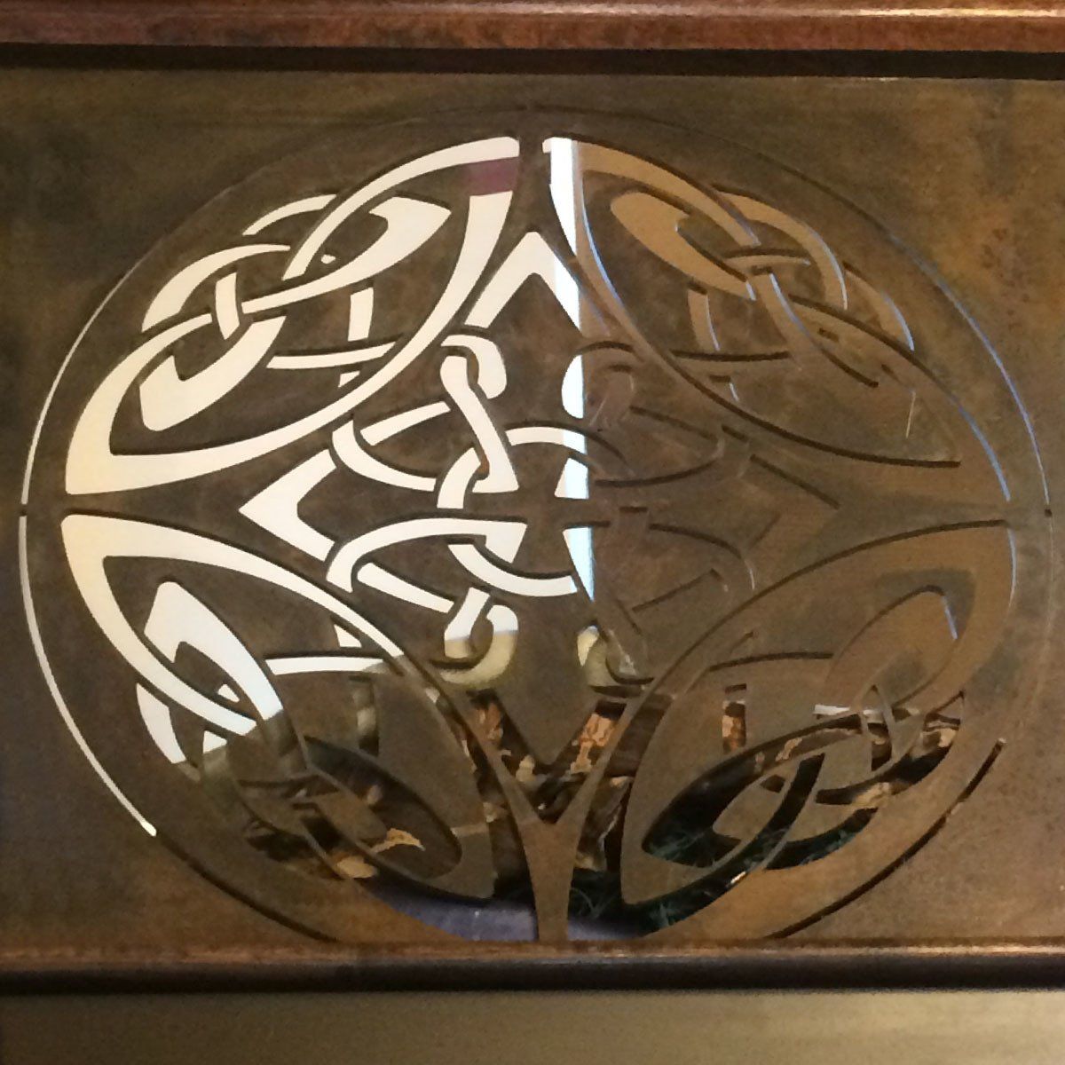 Celtic knot metal medallion on a wooden plaque, in gold and silver tones