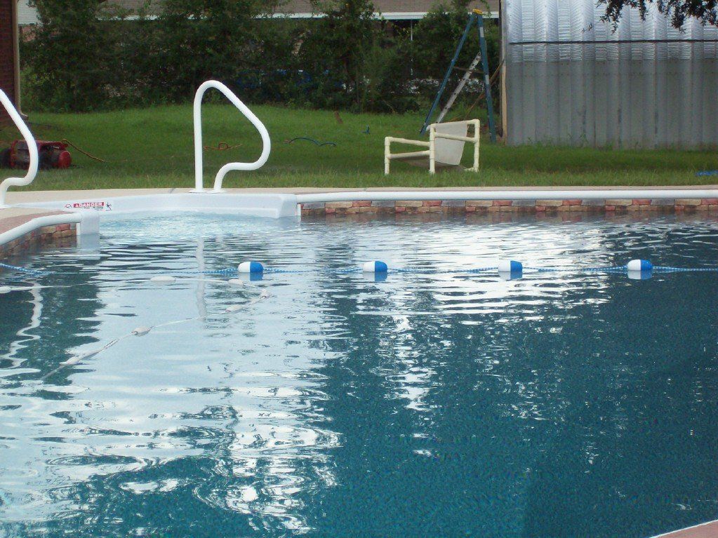 Swimming pool with blue water; white handrails and safety floats.