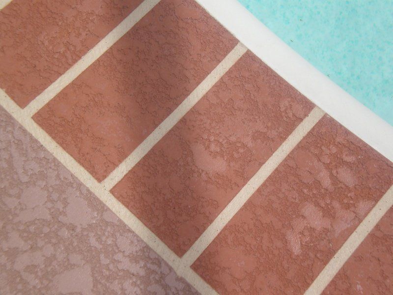 Brick-patterned surface with brown bricks and tan grout, next to a pale pink and light blue area.