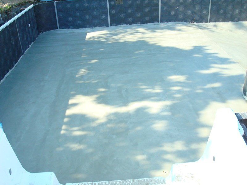 Finished concrete pool interior. Walls are lined with black material.