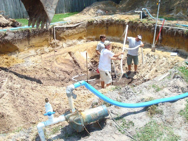 Men working in an excavation, installing pipes for a water system.