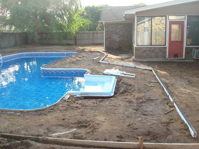 Backyard with a swimming pool, concrete edging, and building with a red door.