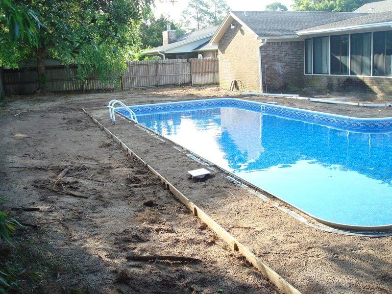 Backyard with a swimming pool, dirt area, and surrounding fence and house.