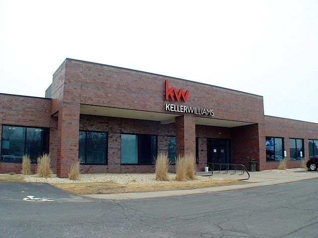 Keller Williams real estate office building with red brick exterior and large windows.