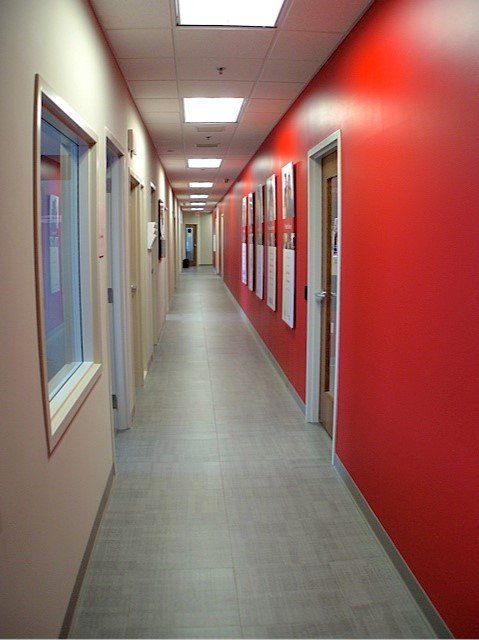 Long hallway with red and beige walls, doors, and a tiled floor.