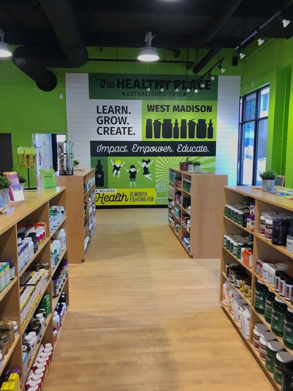 Interior of a health store with aisles of products, green walls, and a sign that says 