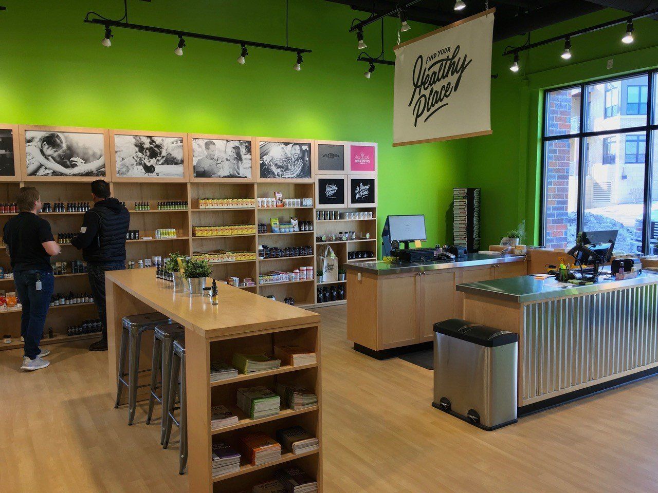 Bright green-walled store interior with customers, display shelves, and a checkout counter.