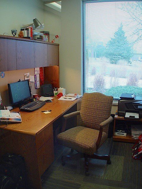 Office desk with computer, chair, and window.