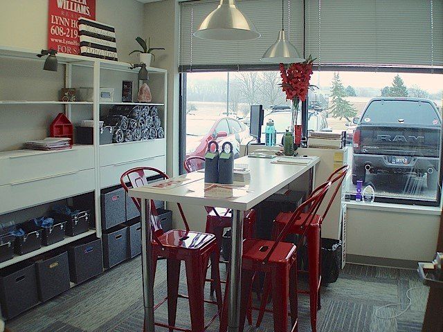 Interior fitness studio with red stools, a table, and shelves with weights and towels.