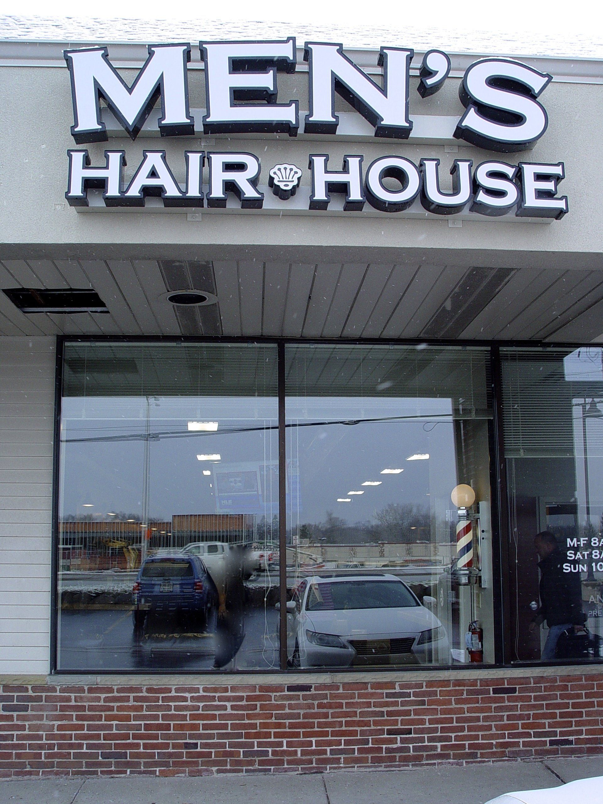 Men's Hair House storefront with large windows, sign, and brick facade. Cars reflected in the glass.