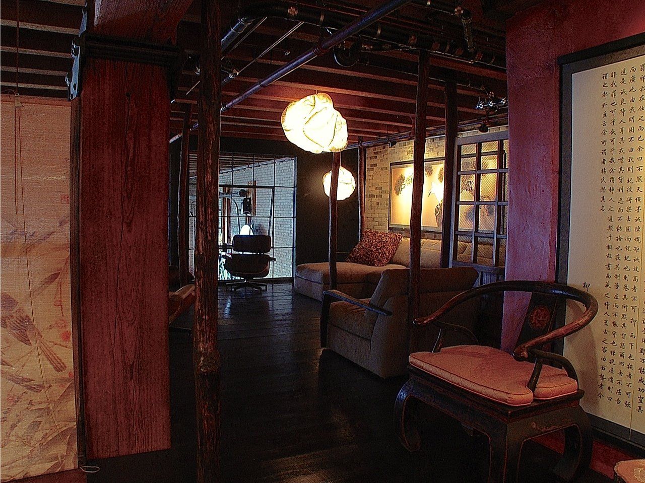 Interior with dark wood beams, red walls, and a sitting area with a chair and couch.