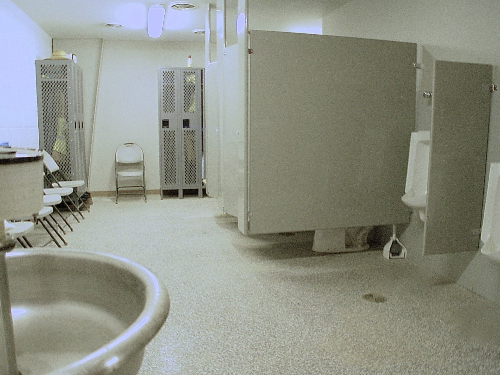 Public restroom with urinals, stalls, lockers, and a sink.