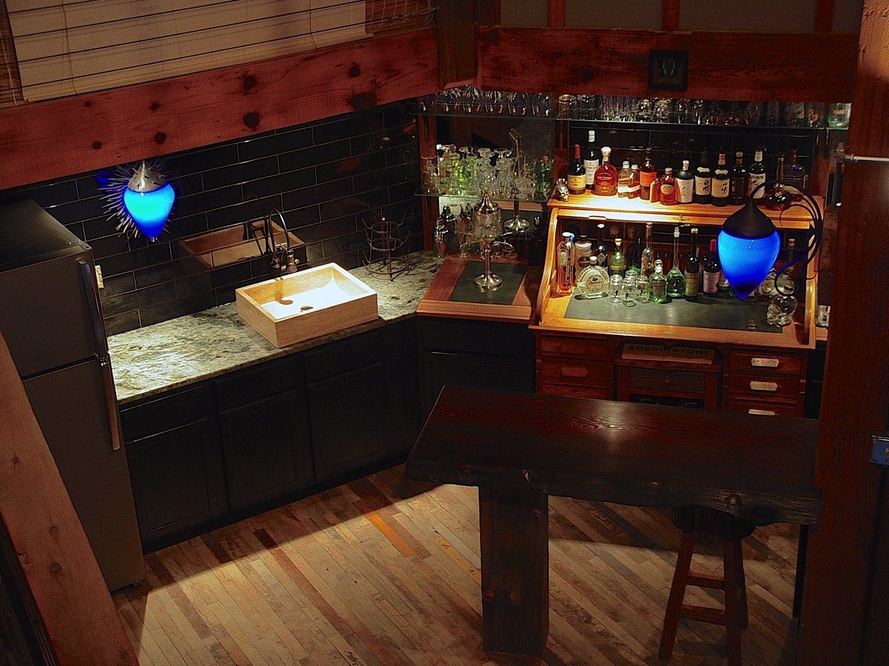 Cozy home bar with dark wood, blue lights, and bottles.