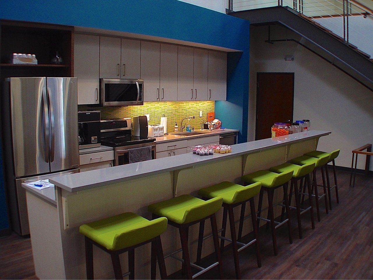 Kitchen area with a bar, stools, stainless steel refrigerator, and microwave.