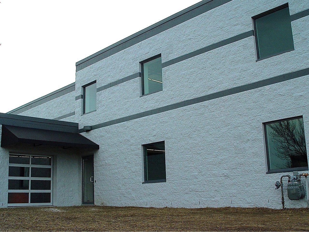 Gray brick building with windows and a black awning.