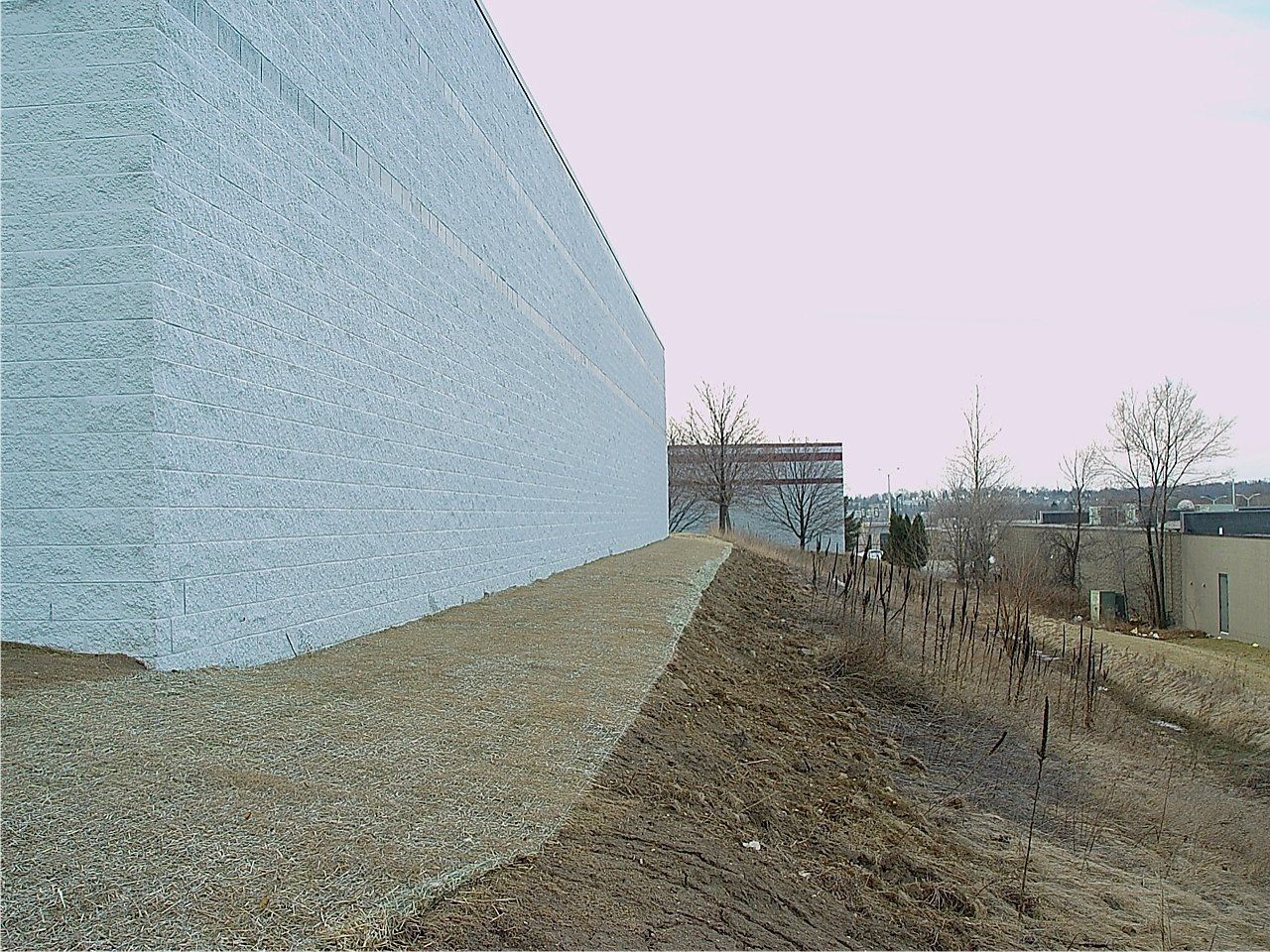 A large structure covered in silver material, set on a gravel base, with a hillside in the foreground.