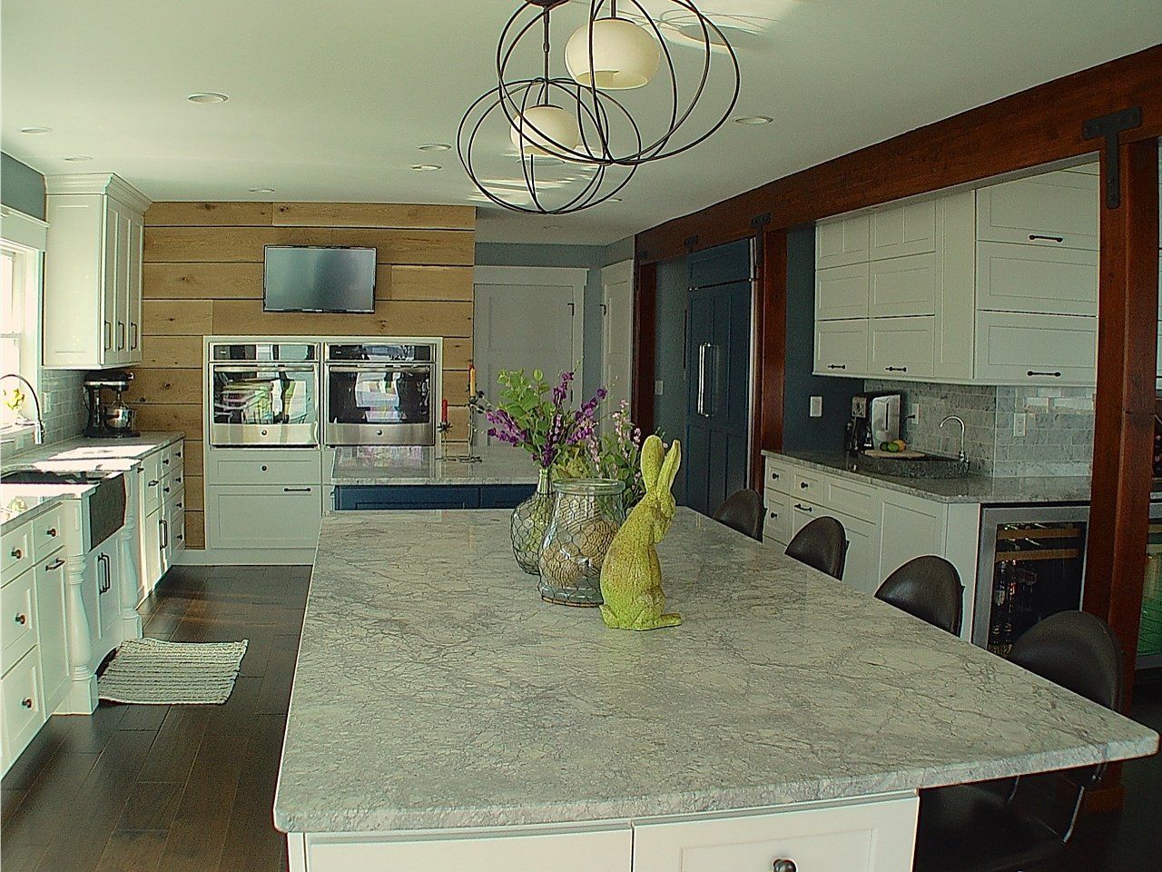 Kitchen with large gray countertop island, light cabinets, and wood accents.