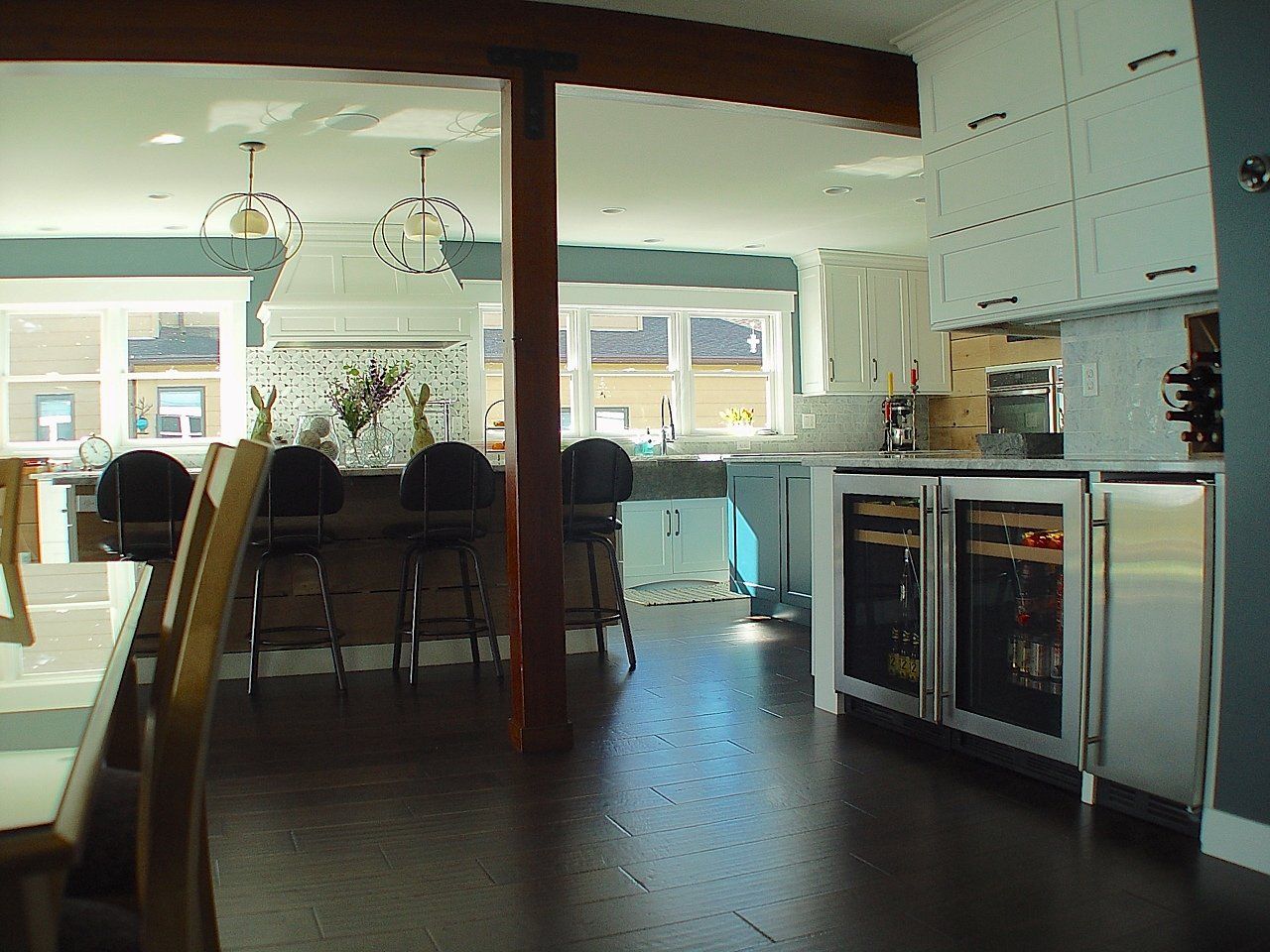 Spacious kitchen with dark wood floors, white cabinets, and stainless steel wine coolers.