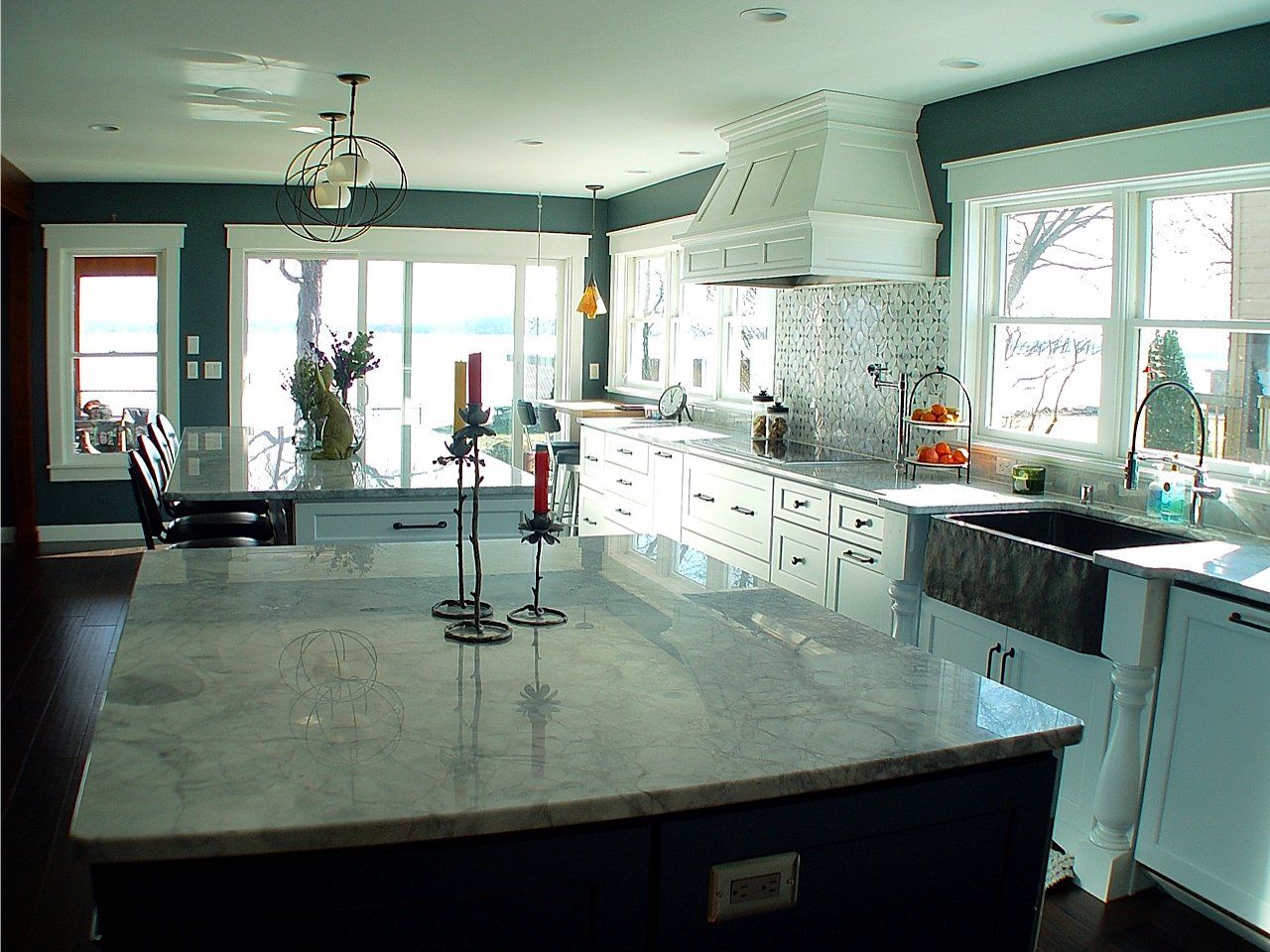 Spacious kitchen with a large island and white cabinets. Windows provide natural light.
