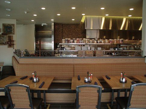 Restaurant interior with tables, booths, and open kitchen visible in the background.