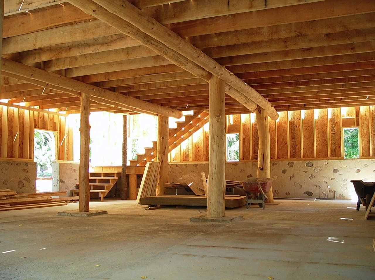 Interior of a building under construction, showing wooden beams, walls, and staircase.