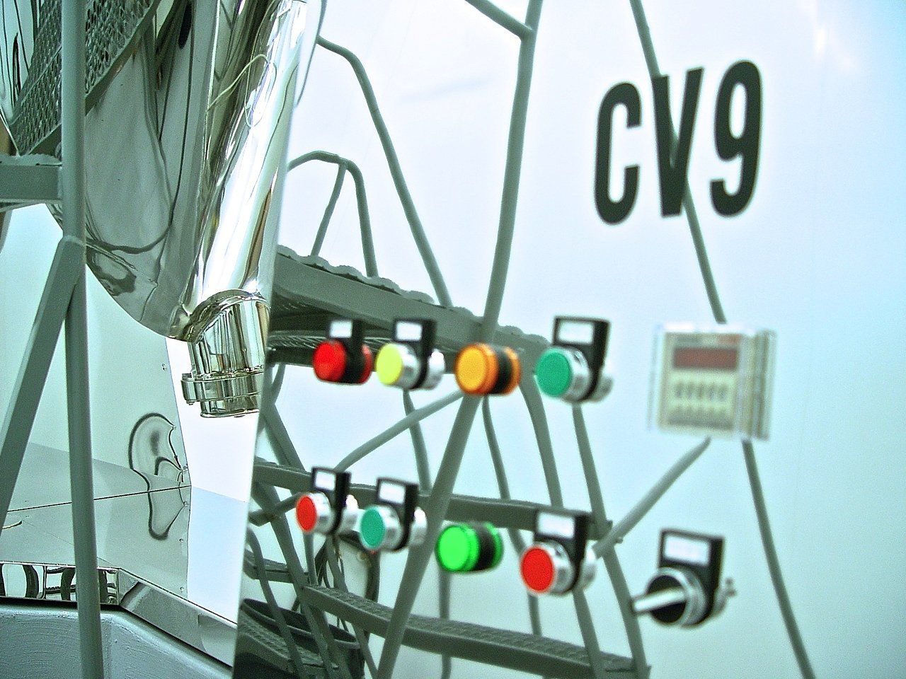 Control panel with lights and digital display next to a Ferris wheel structure and 