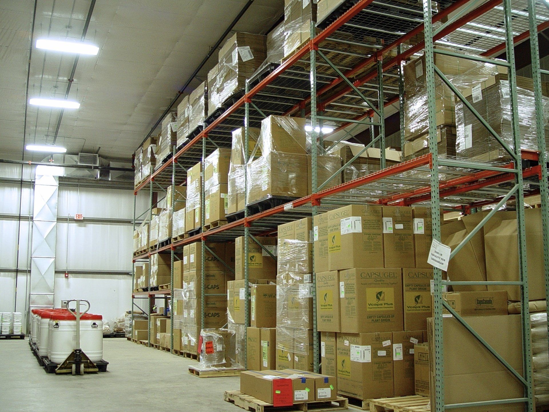 Warehouse interior with shelves of stacked cardboard boxes.
