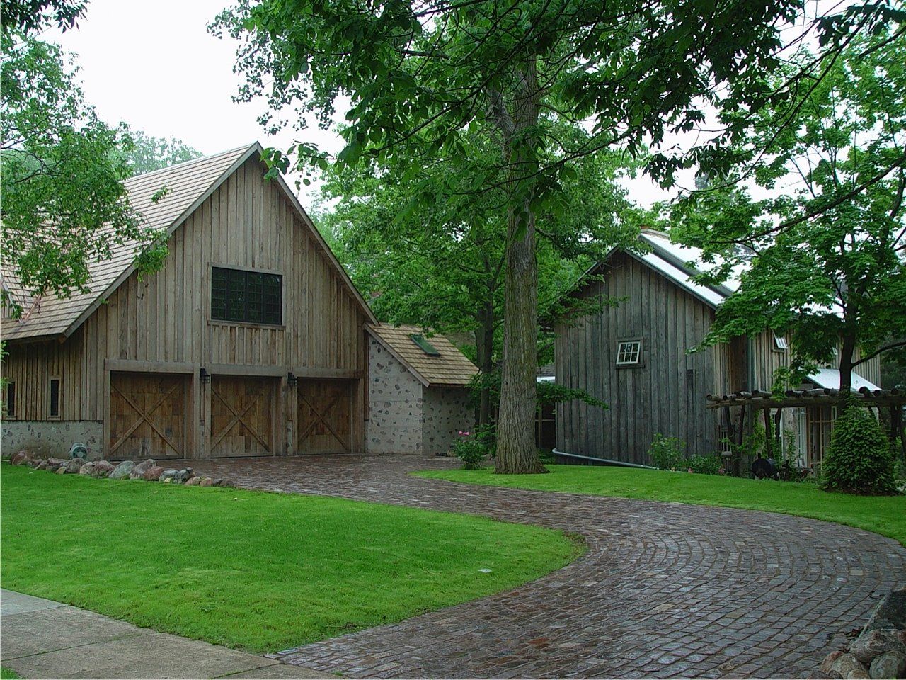 Wooden barns with a gravel driveway and green lawn.