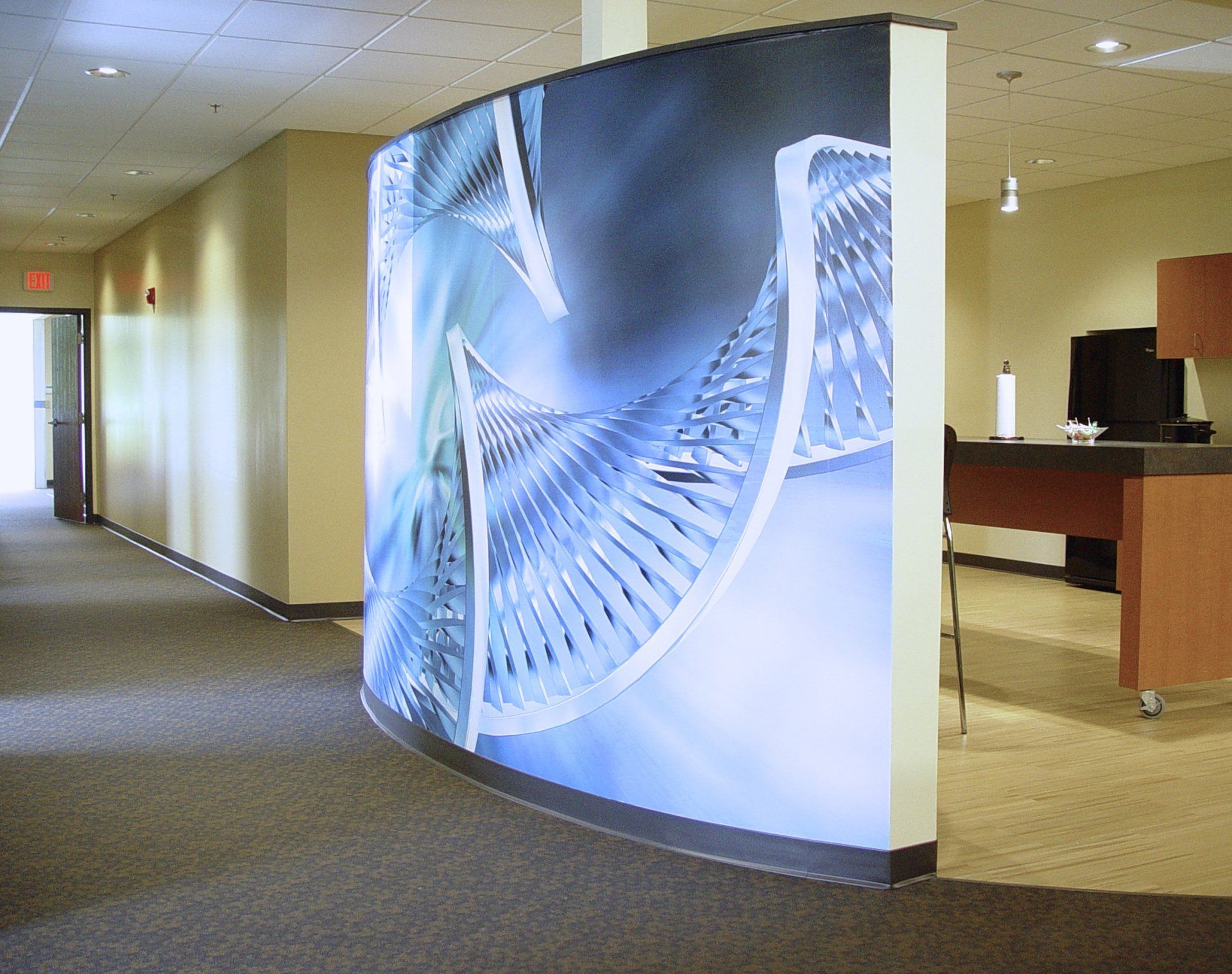 Curved wall with abstract blue graphic in an office hallway.