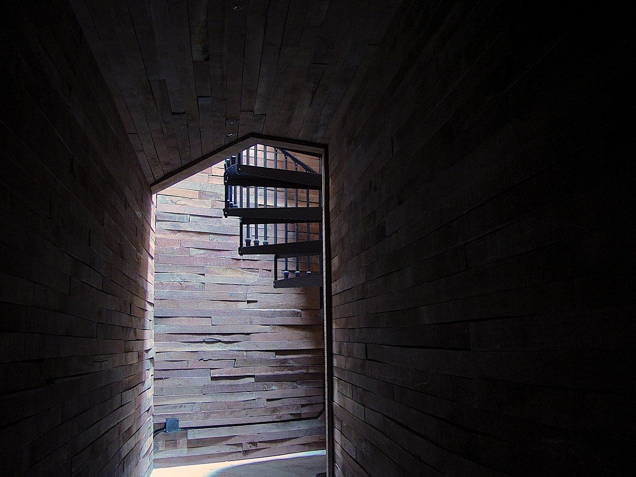 Dark wooden corridor leading to a spiral staircase.