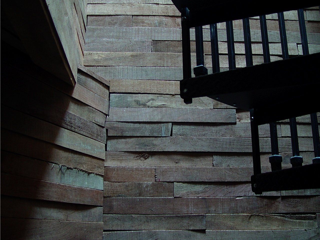 Stairwell with stone walls and a black metal spiral staircase descending.