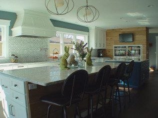 Bright modern kitchen with large island, blue cabinets, white countertops, and decorative items.