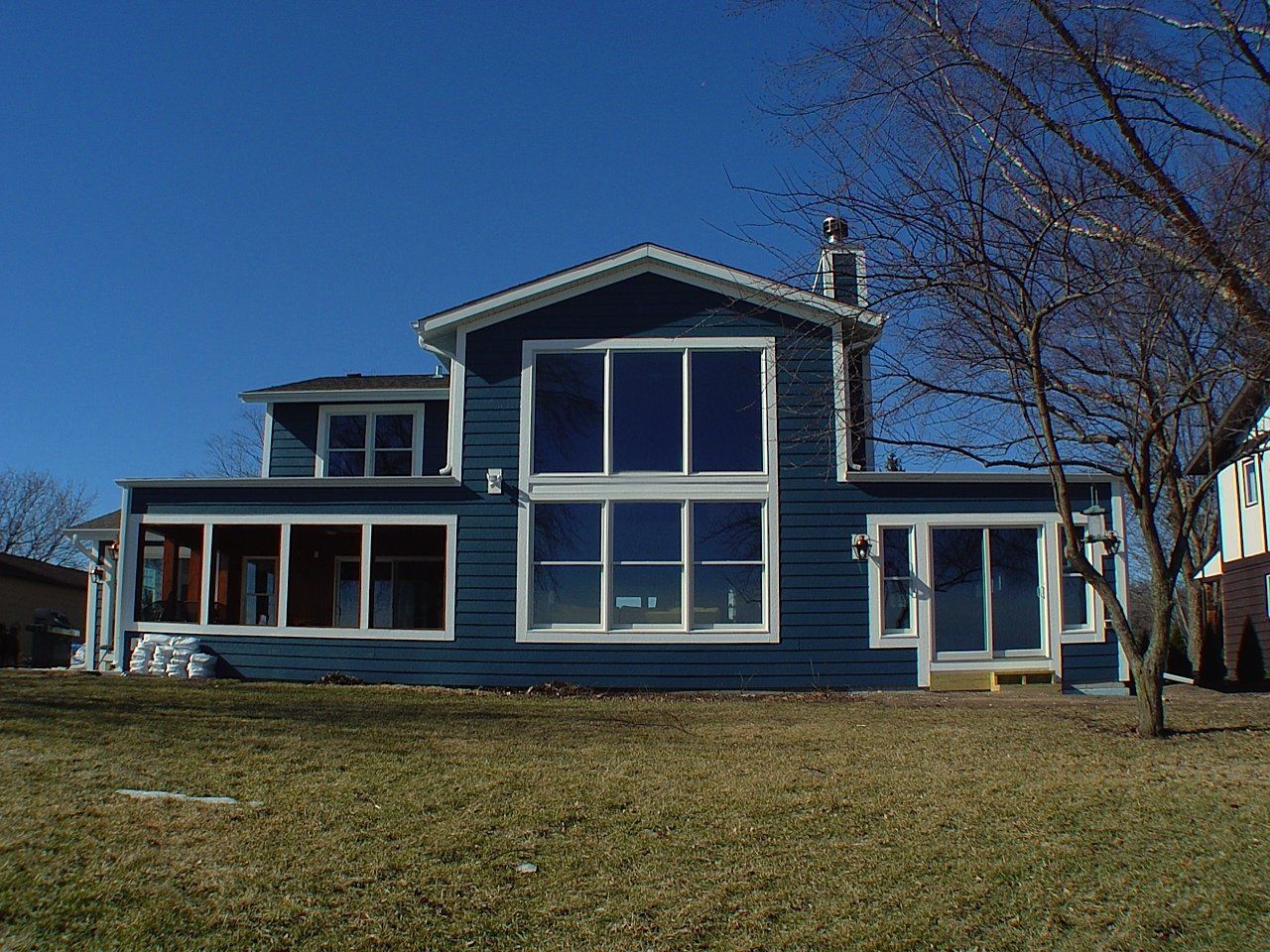 Blue house with large windows under a clear blue sky; sunny day.