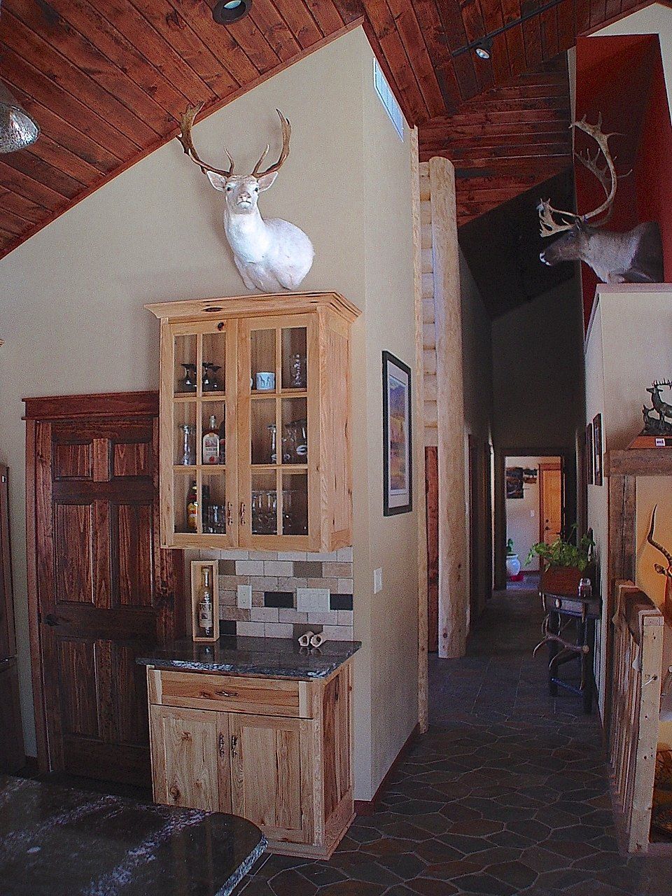Rustic home interior with a small bar, a mounted deer head, and a hallway.