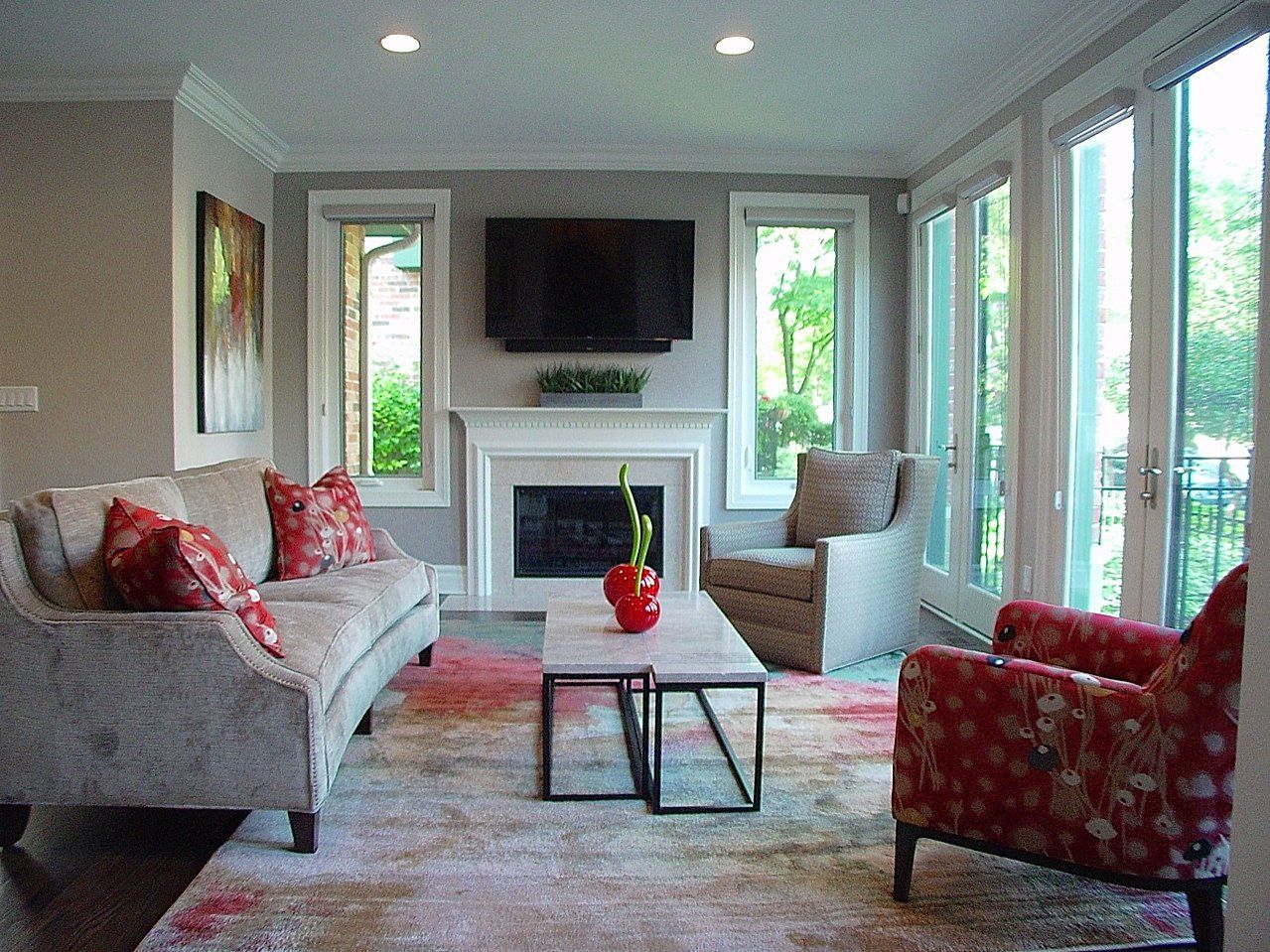 Living room with gray walls, sofa, patterned rug, fireplace, TV, and French doors.