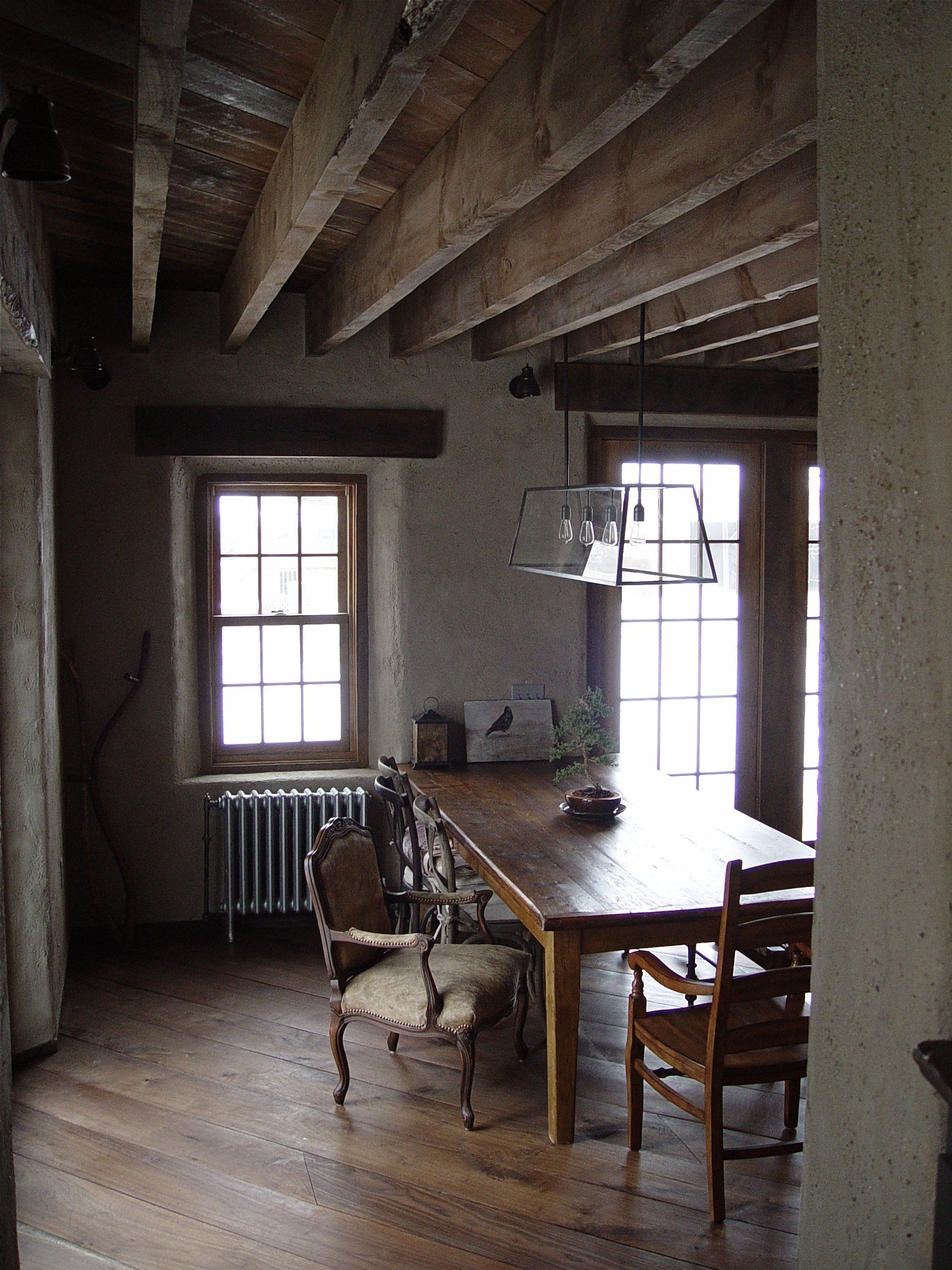 Dining room with wooden table and chairs, window, door, and exposed wood beams.