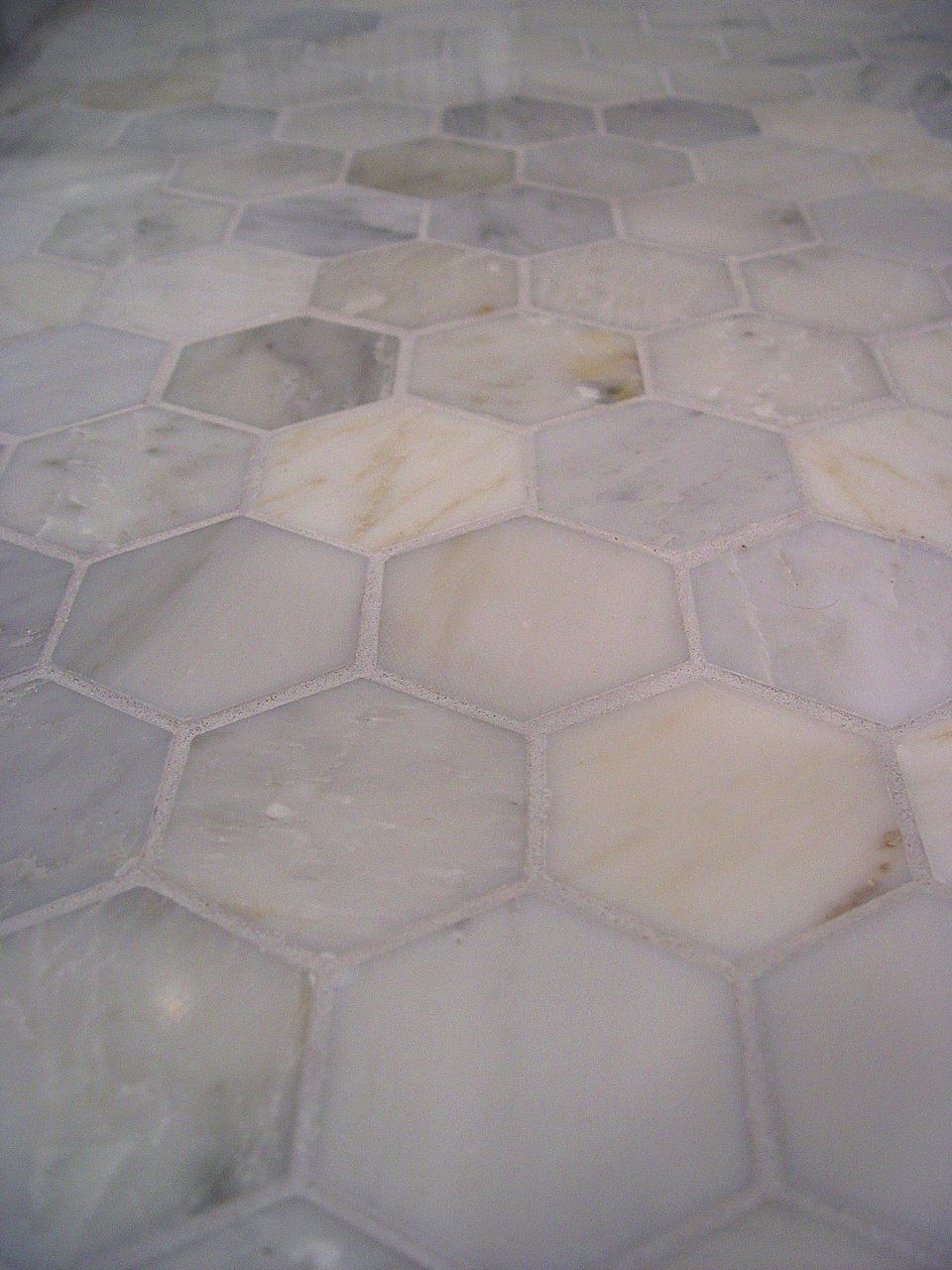 Close-up of hexagonal marble tiles in shades of gray, white, and beige.