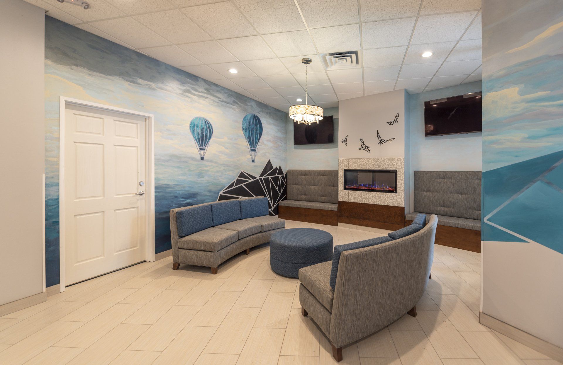 Waiting room with blue and gray furniture, fireplace, and hot air balloon mural.