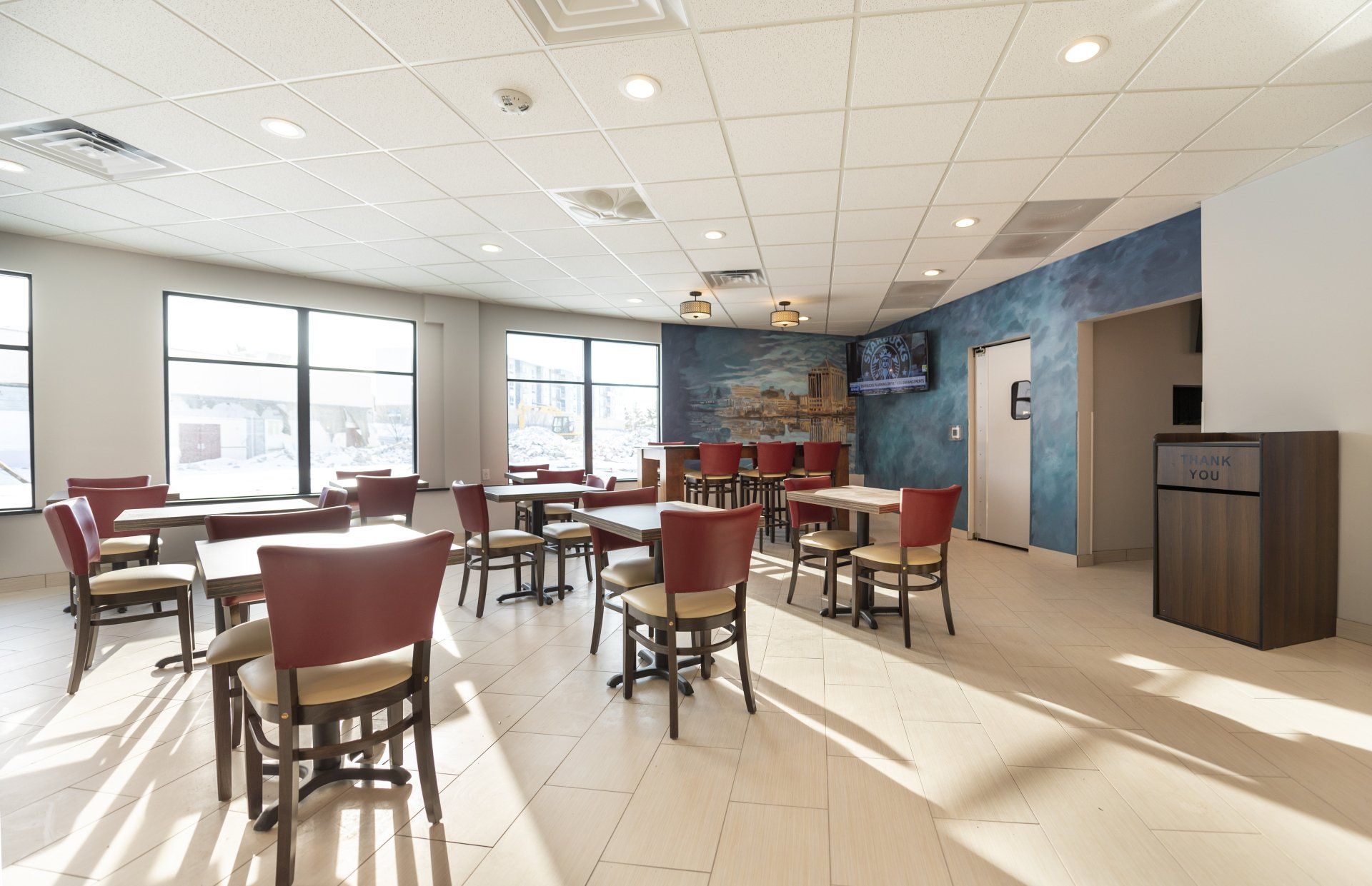 Bright dining area with tables, chairs, windows, and a blue accent wall.