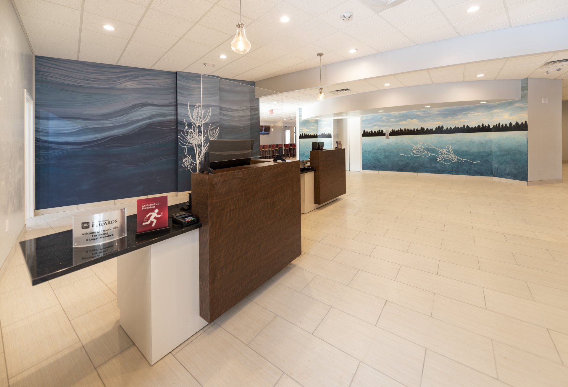 Hotel lobby with reception desk, artwork of water, and bright tiled floor.
