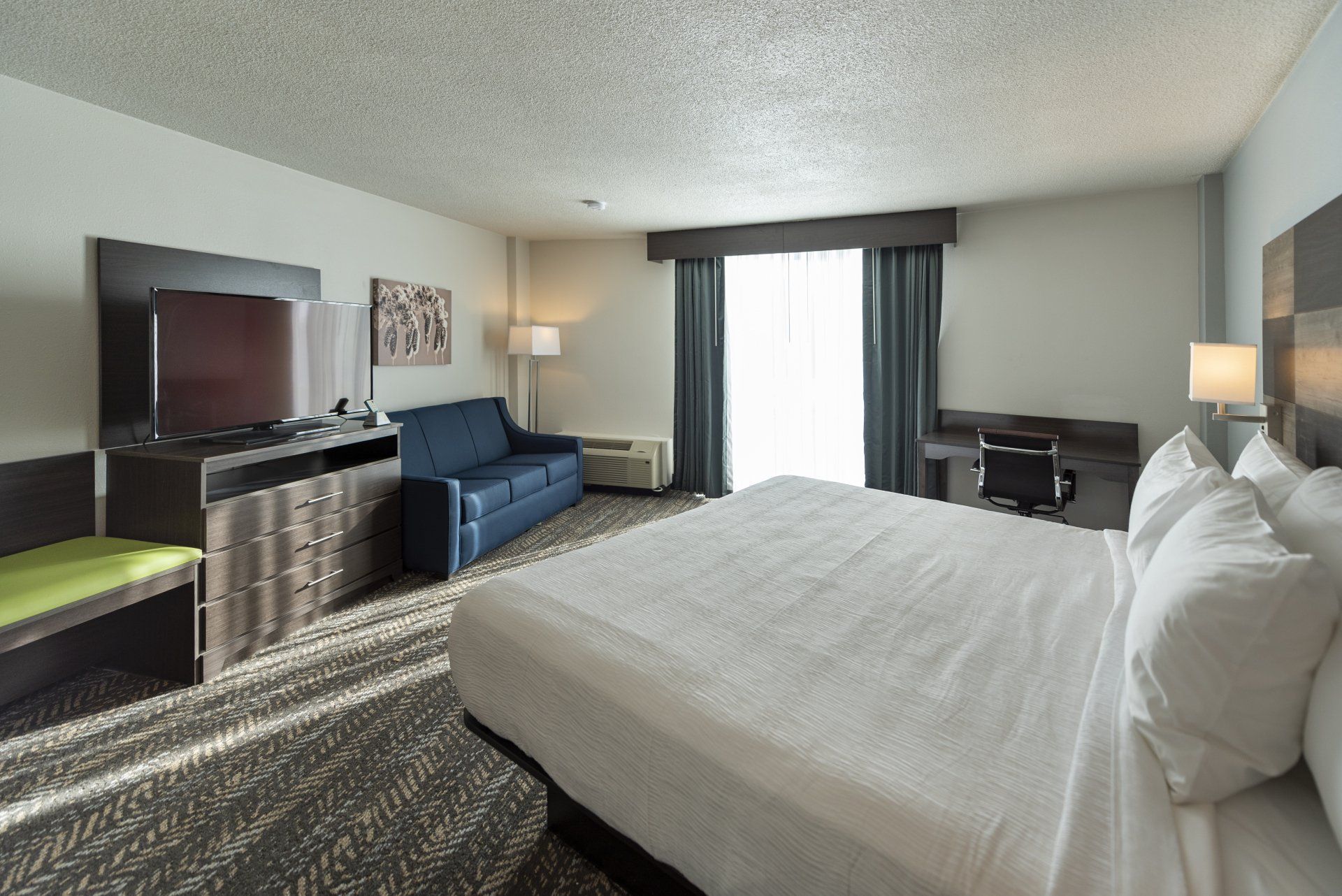 Hotel room with a bed, desk, sofa, and TV.