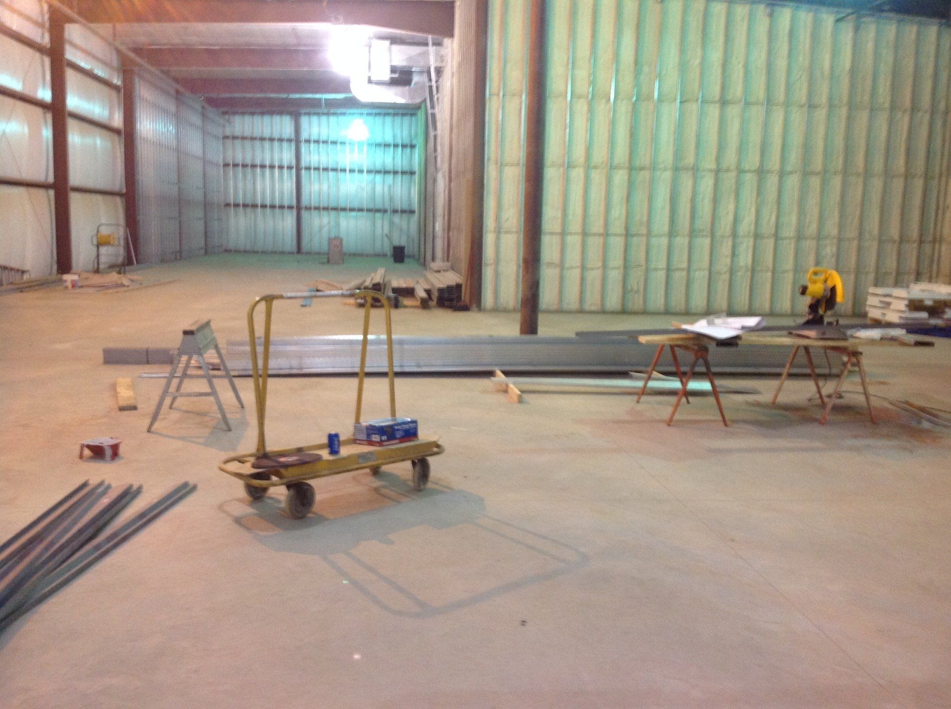Interior of a warehouse under construction, with tools and materials on the floor.