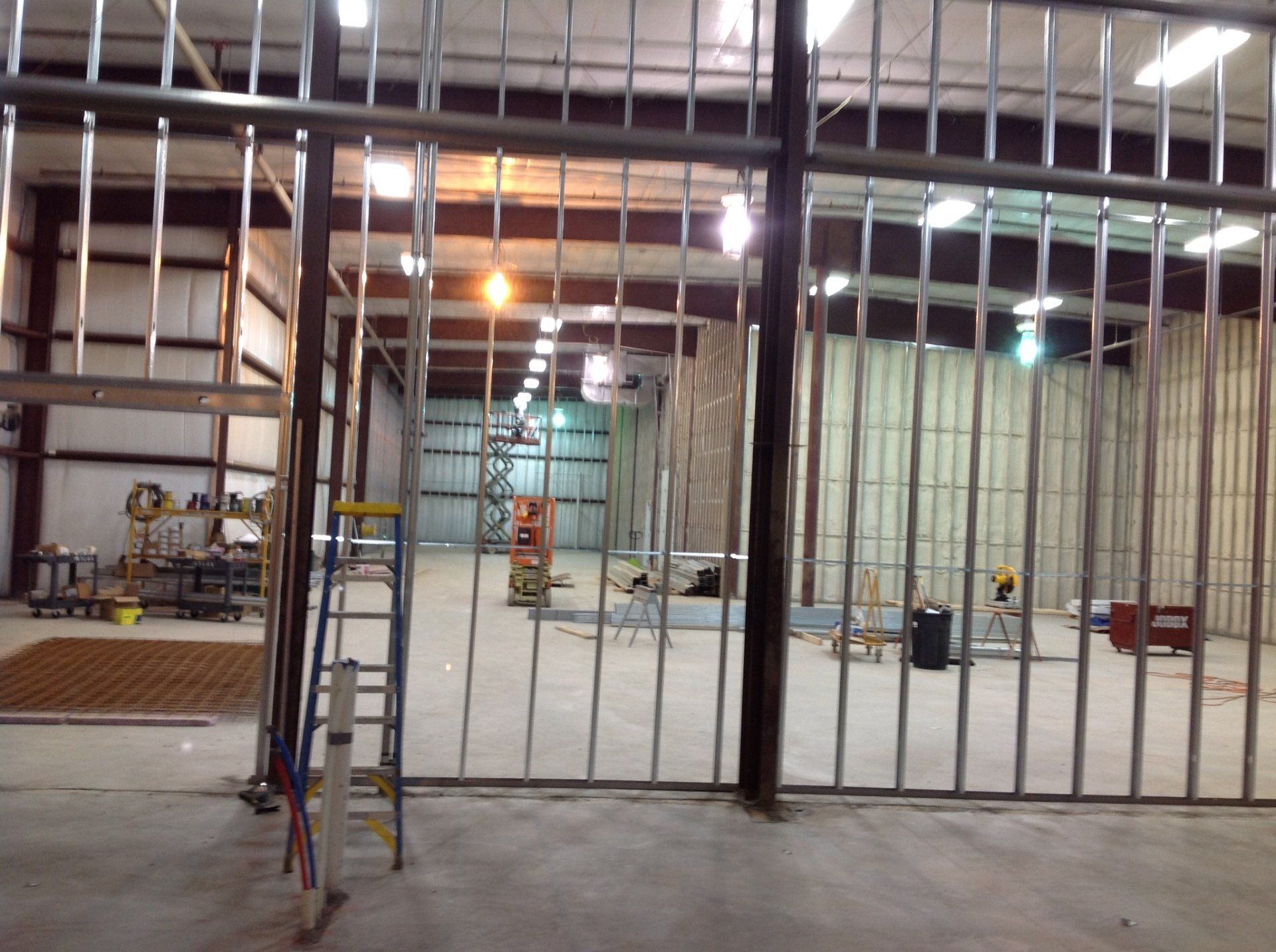 Interior of a building under construction. Metal framing and walls are visible, along with tools and equipment.