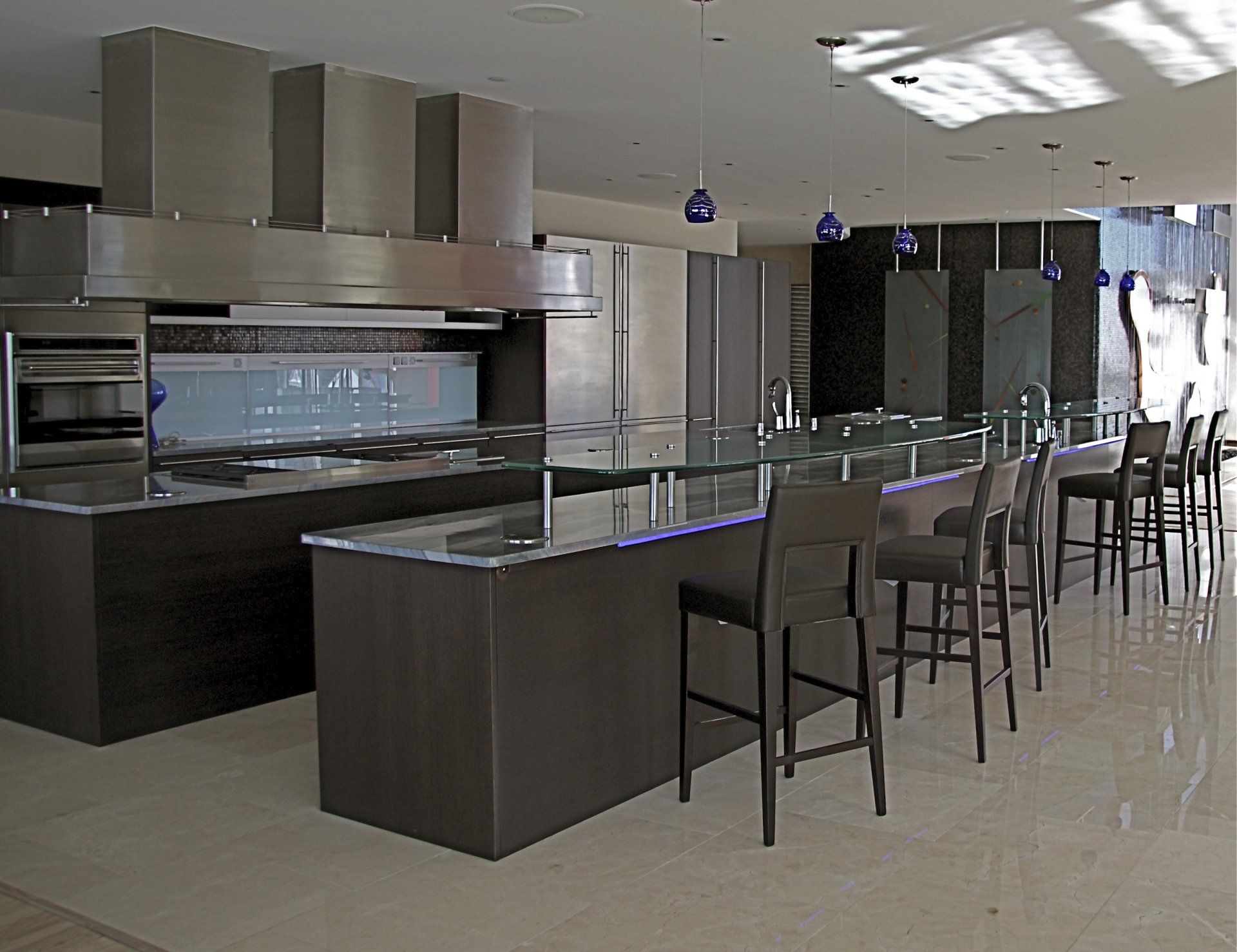Modern kitchen with dark brown cabinets, stainless steel appliances, and a long island with bar stools.