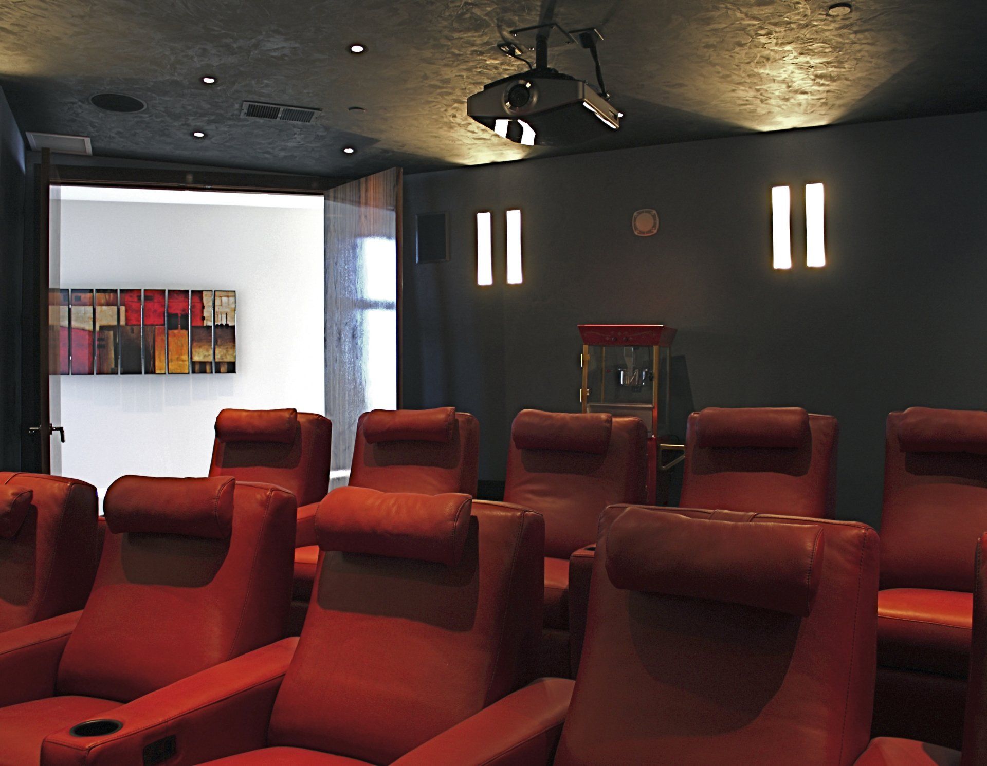 Red leather home theater seating; popcorn machine; projector; dark walls and ceiling.