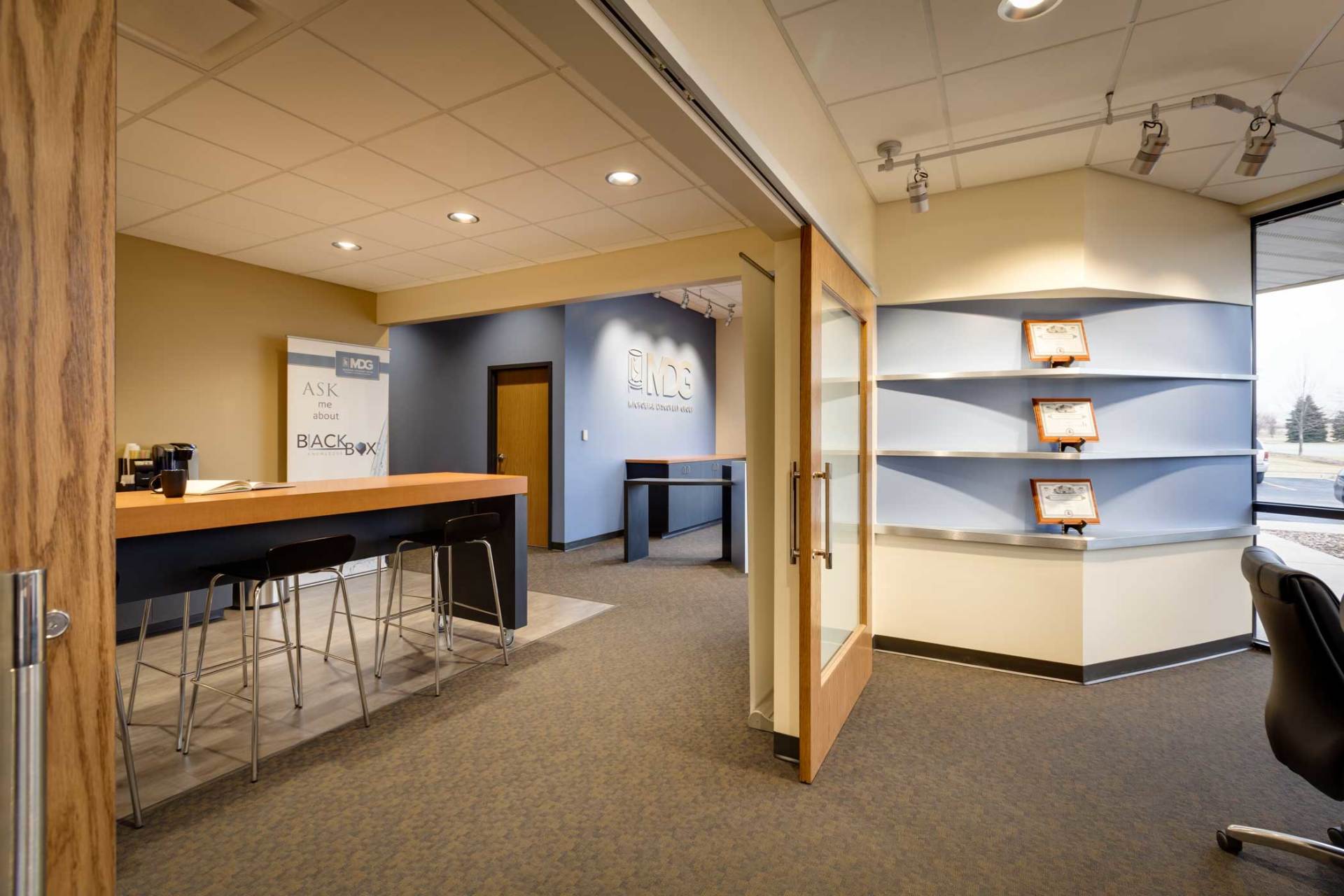 Office interior with open doors, a long counter with stools, and built-in shelves.
