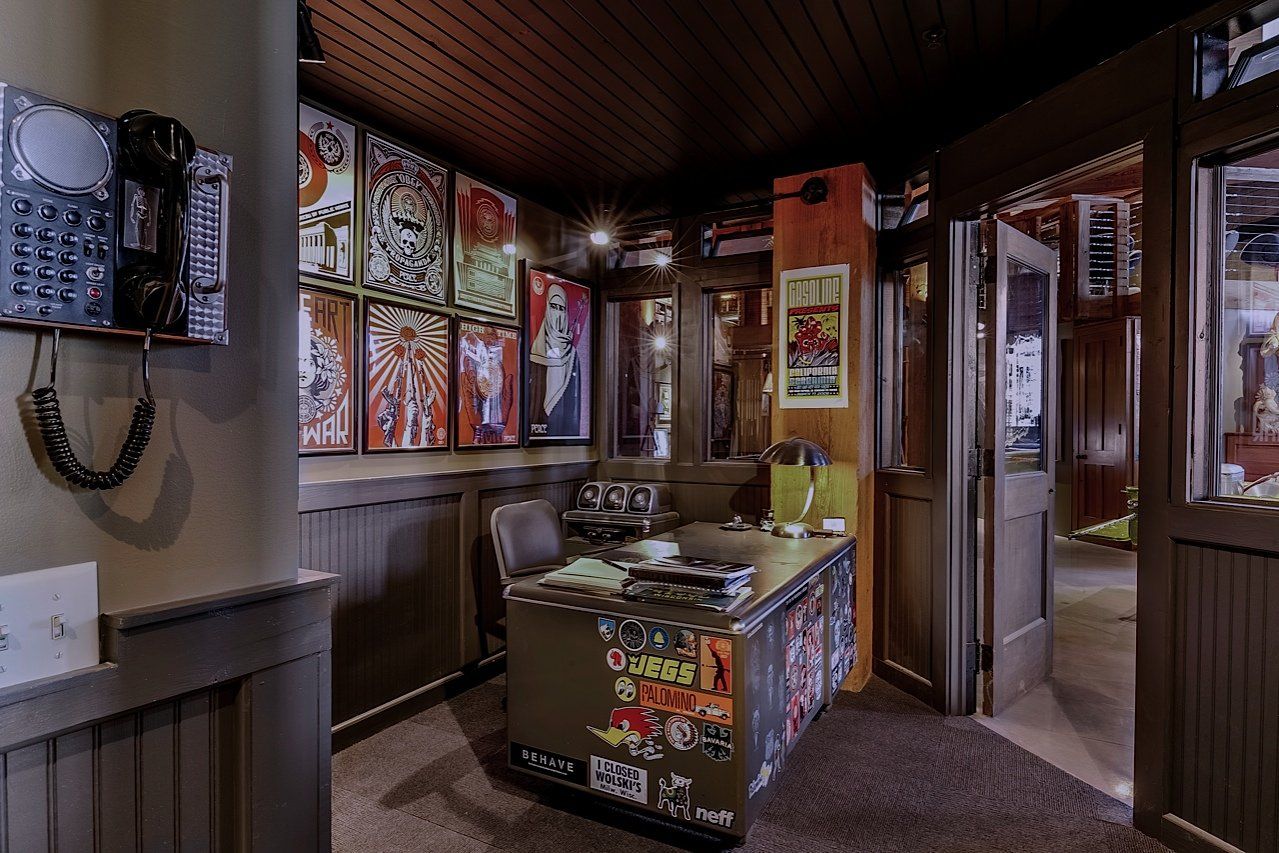 A wood-paneled office with a desk covered in posters, vintage phone, and posters on the wall.