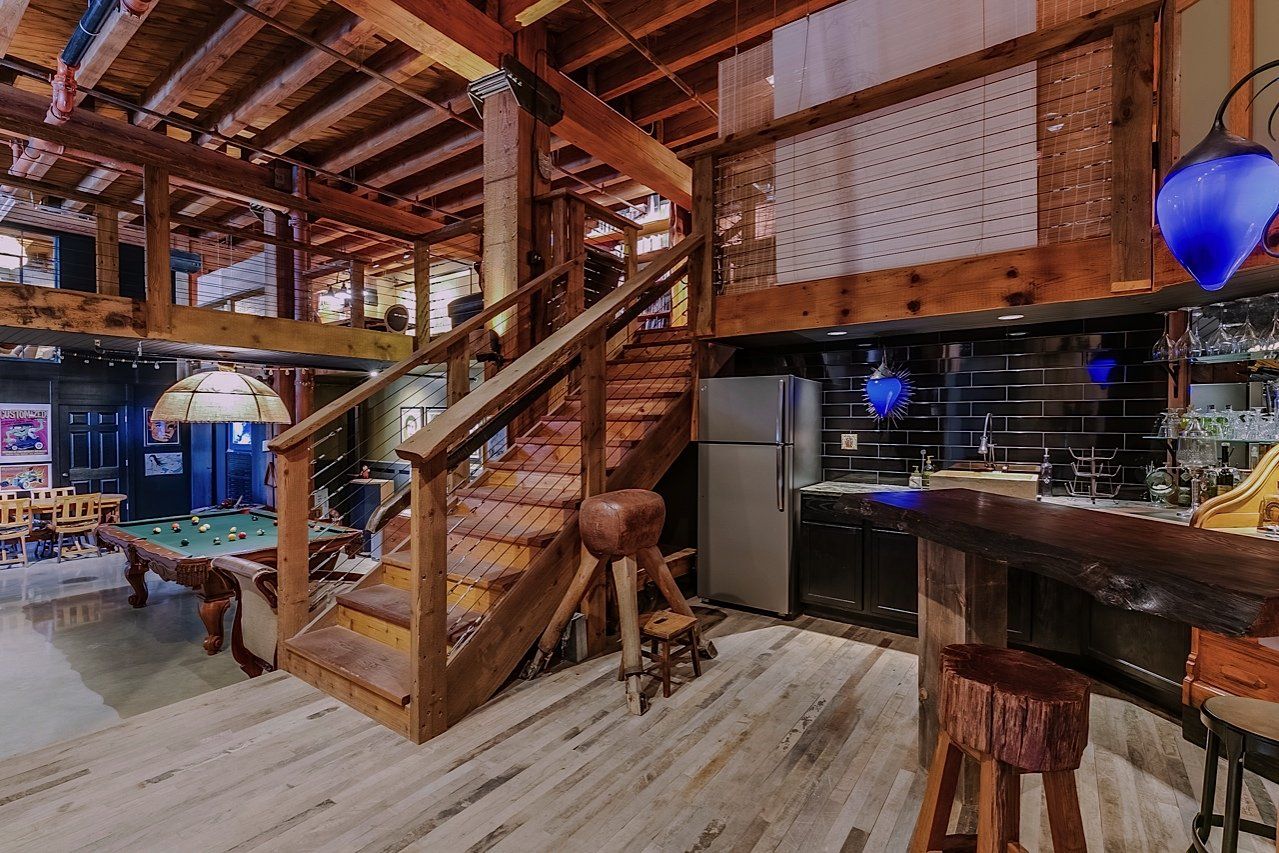 Rustic interior with wooden stairs, bar, and pool table.